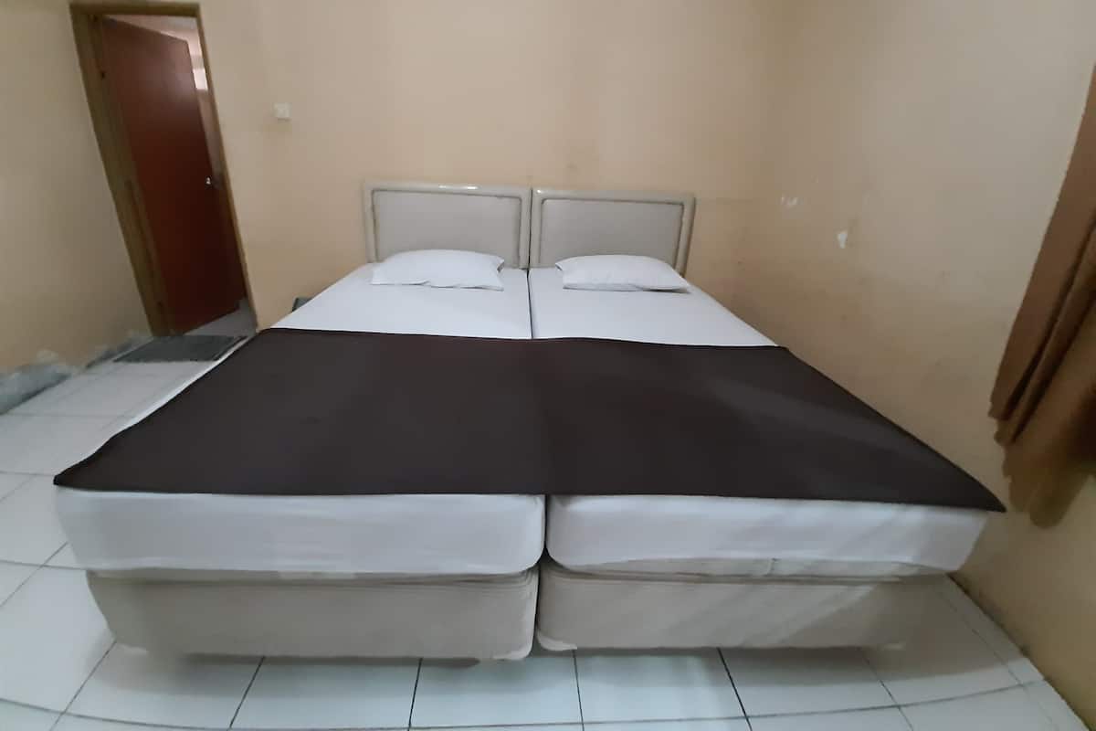 A double bed with white linens, a dark-colored blanket, and a headboard.