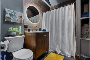 A modern bathroom with a toilet, sink, and shower curtain. - #28- *Modern Bungalow* (New Britain)