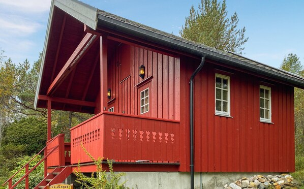 Situated in a serene natural setting, this cabin features a steeply pitched roof and a charming porch area with a prominent staircase.