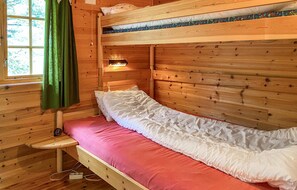 Cozy cabin room with a bunk bed, bedside table, and wall-mounted lamp.