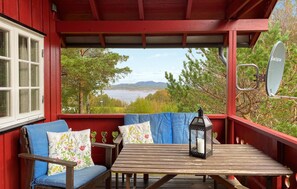 Relax in this serene outdoor seating area with a wooden table and two cushioned chairs, surrounded by a tranquil landscape.