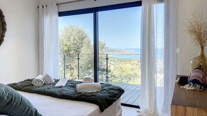 A bedroom with a large bed, a view of the sea, and a wooden desk with a vase. - Villa Casa di C (Corbara)