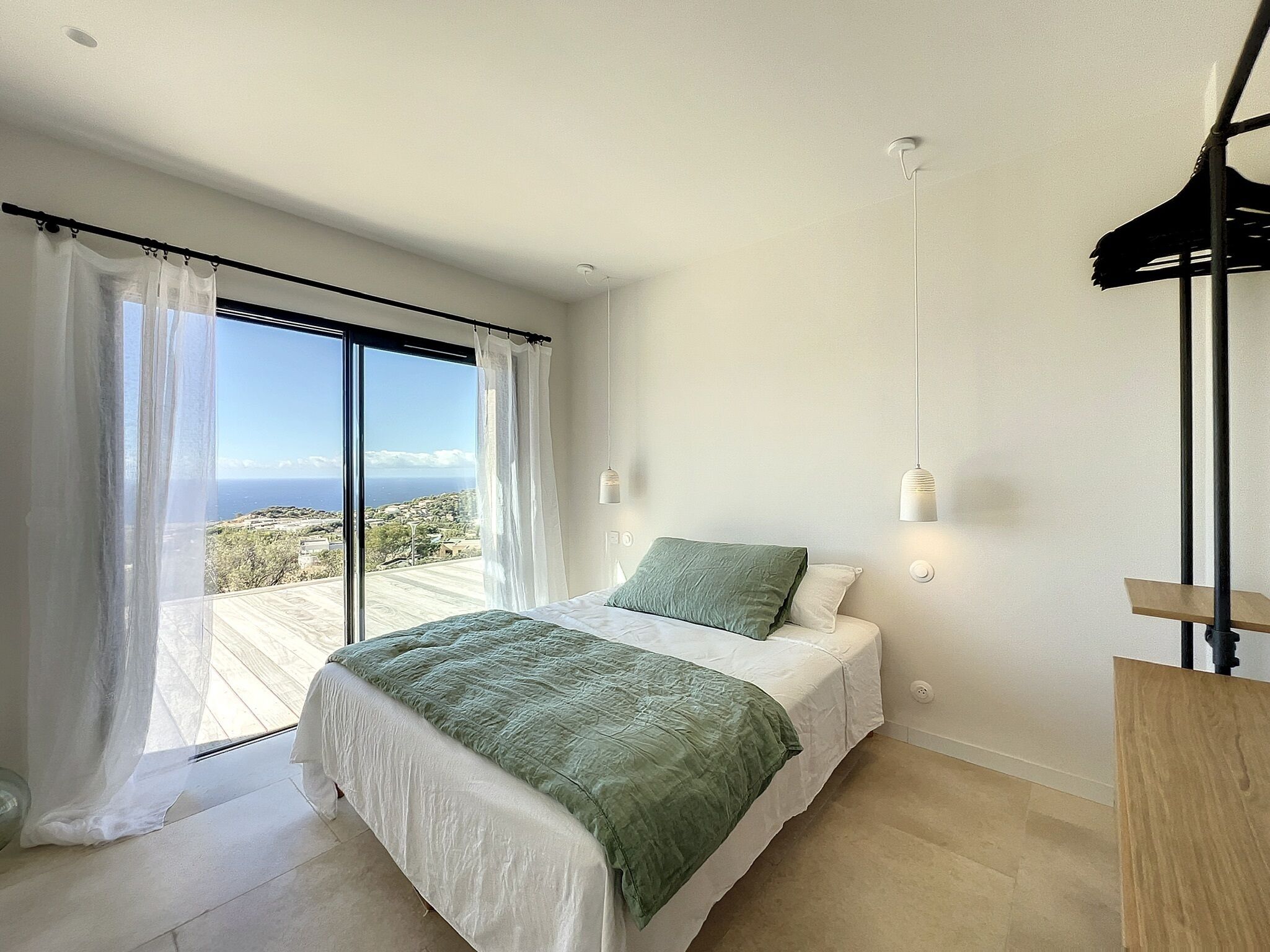 A bedroom with a bed, a view of the sea, and a balcony.