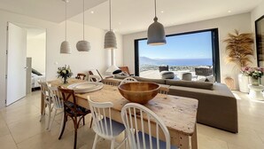 A modern dining area with a large table, white chairs, and hanging pendant lights. - Villa Casa di C (Corbara)