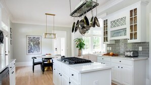 Une cuisine moderne avec des meubles blancs, un îlot central et un porte-ustensiles suspendu.