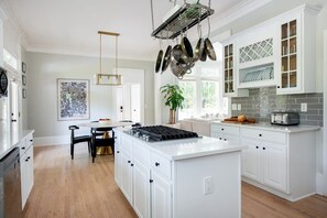 A modern kitchen with white cabinetry, a central island, and a hanging pot rack.