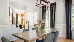 Un coin repas avec une table en bois, des chaises grises et un centre de table floral.