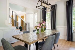 A dining area with a wooden table, grey chairs, and a floral centerpiece.