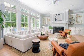 Ein geräumiges Wohnzimmer mit einem weißen Sofa, einem Ledersessel und einem Kamin.