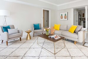 Una sala de estar moderna con un sofá, dos sillones, una mesita de centro y una lámpara de pie.