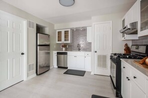 Una cocina moderna con armarios blancos, electrodomésticos de acero inoxidable y un backsplash de azulejos.