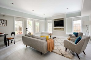 A modern living room with a grey sofa, a coffee table, and a TV mounted on the wall.
