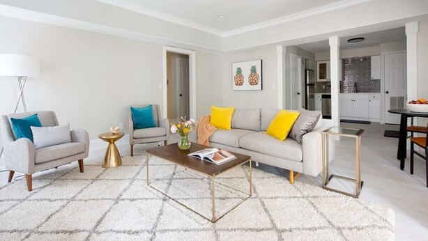 A modern living room with a sofa, armchairs, a coffee table, and a dining area.
