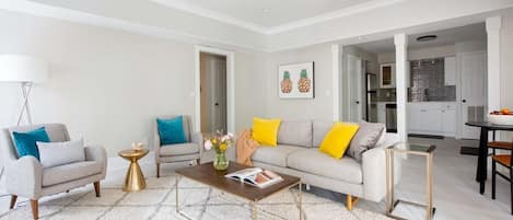 A modern living room with a sofa, armchairs, a coffee table, and a dining area.