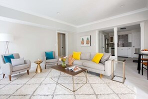 A modern living room with a sofa, armchairs, a coffee table, and a dining area.