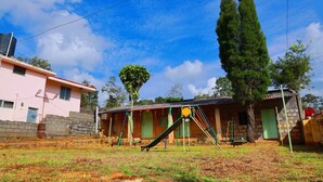 A residential area with a pink house, a wooden play structure, and a tall tree.