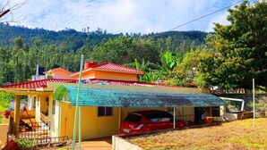A yellow house with a red roof, a carport, and a small porch.