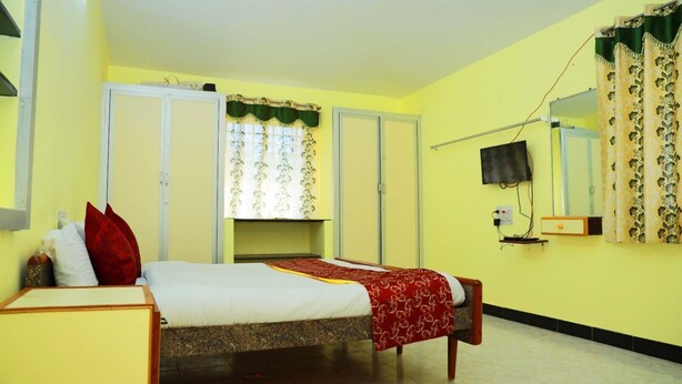 A bedroom with a bed, a wardrobe, a mirror, and a television.
