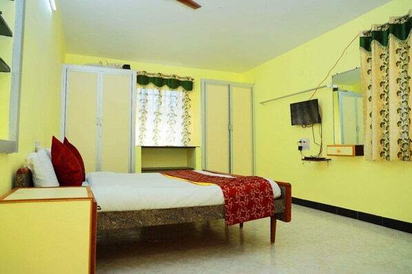 Un dormitorio con cama, armario, espejo y televisor.