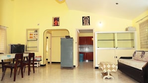 A compact living space with a dining area, kitchen, and a sofa. - Rena Home Stay (Yercaud)