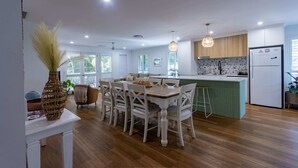 Une cuisine moderne avec un coin repas, un plancher en bois et des luminaires suspendus.