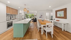 Uma cozinha moderna com ilha central, piso de madeira e iluminação pendente.