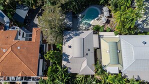 Vue aérienne d’un quartier résidentiel avec une piscine, plusieurs maisons et une végétation luxuriante.