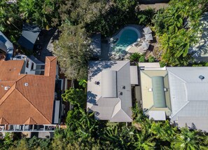 An aerial view of a residential area with a swimming pool, multiple houses, and lush greenery.