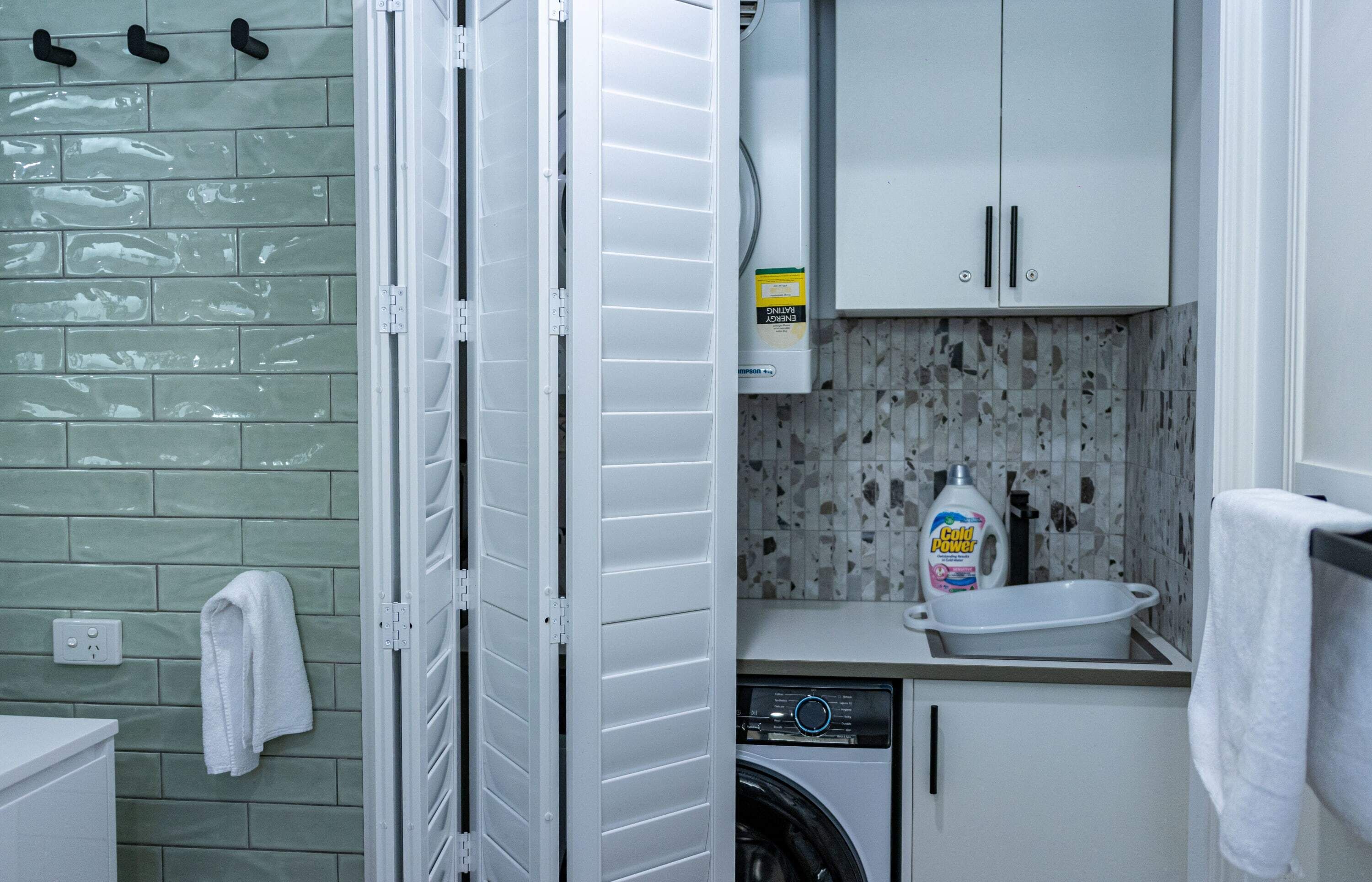 A compact laundry room with a washing machine, a sink, and cabinets.