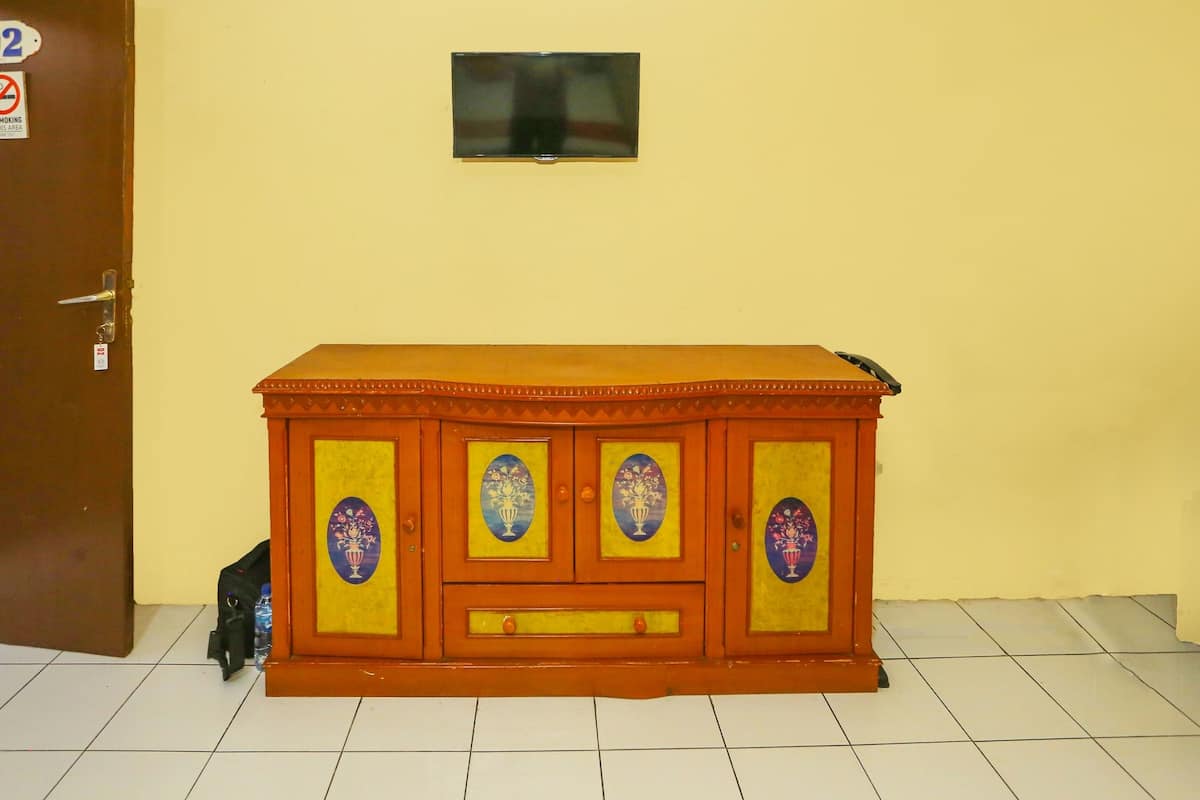 Ein Holzkabinett mit verzierten Paneelen und einem an der Wand befestigten Fernseher.