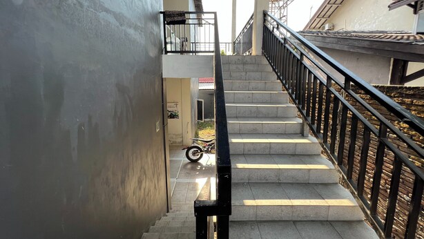 Un escalier avec une rampe en métal, menant à un niveau supérieur.