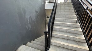 Un escalier avec une rampe en métal noir et un mur gris.