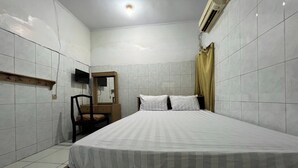 Une chambre à coucher avec un lit, une chaise, une étagère en bois, une télévision et un miroir.