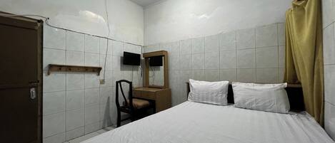 A hotel room with a bed, a wooden dresser, a chair, a television, and a door.