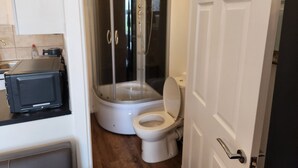 A compact bathroom with a shower enclosure, a toilet, and a microwave. - 1 Bed Flat - Sleeps 3 - Parking - Wifi (Greenhithe)