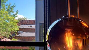 A view through a window with a hanging light bulb and a hotel sign in the background.