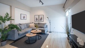 A modern living room with a grey sofa, two round coffee tables, and a large flat-screen TV. - Modern Apartment with Acropolis view (Athens)