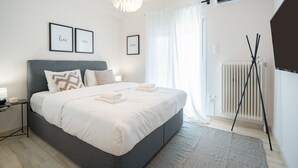 A modern bedroom with a large bed, bedside tables, a standing lamp, and a radiator. - Modern Apartment with Acropolis view (Athens)