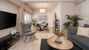 A modern living room with a flat-screen TV, grey armchair, round coffee table, and a grey sofa. - Modern Apartment with Acropolis view (Athens)
