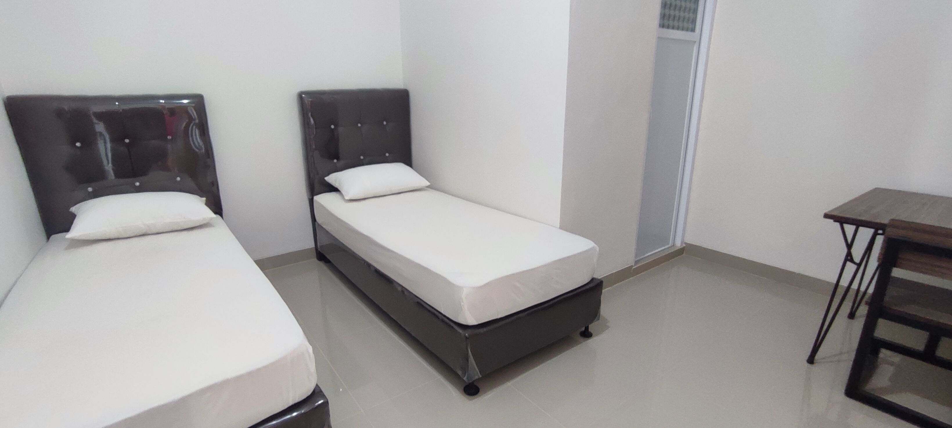 A room with two single beds, a small table, and a door.