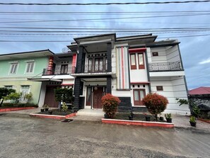 A modern two-story house with a balcony, a garage, and a driveway. - OYO 93143 Mega Raudhah Syariah (Tanah Datar)