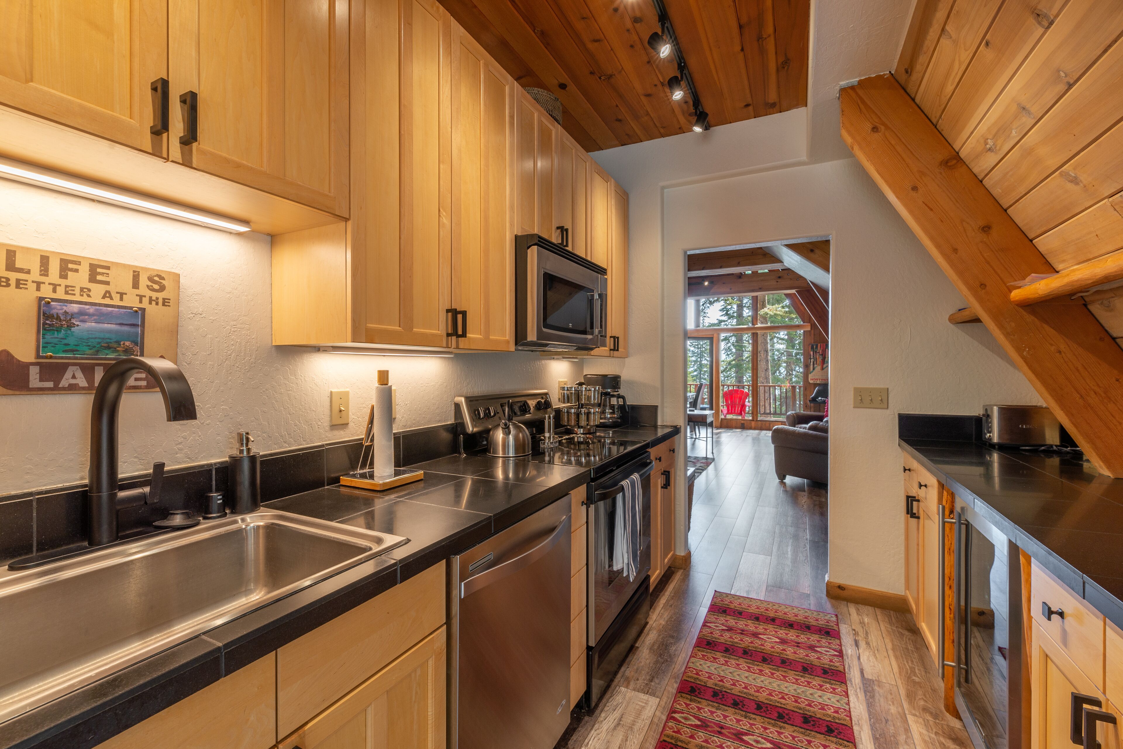 A modern kitchen with wooden cabinets, stainless steel appliances, and a black countertop.