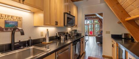 A modern kitchen with wooden cabinets, stainless steel appliances, and a black countertop.