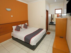 A hotel room with a bed, a wooden headboard, a small bathroom with a mirror, and a wooden cabinet. - Hotel O Puncak Bogor Near Taman Safari Formerly Alam Hegar (Cisarua)