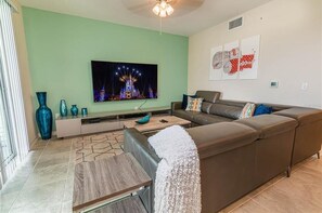A modern living room with a large flat-screen TV, a brown leather sofa, and a coffee table. - The Epic 32 Supreme Storey Lake Resort Orlando FL (Kissimmee)
