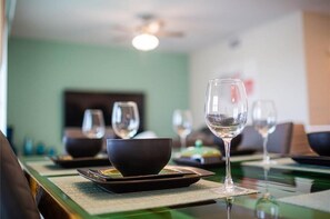 Uma sala de jantar com mesas preparadas para uma refeição, incluindo tigelas e copos de vinho.