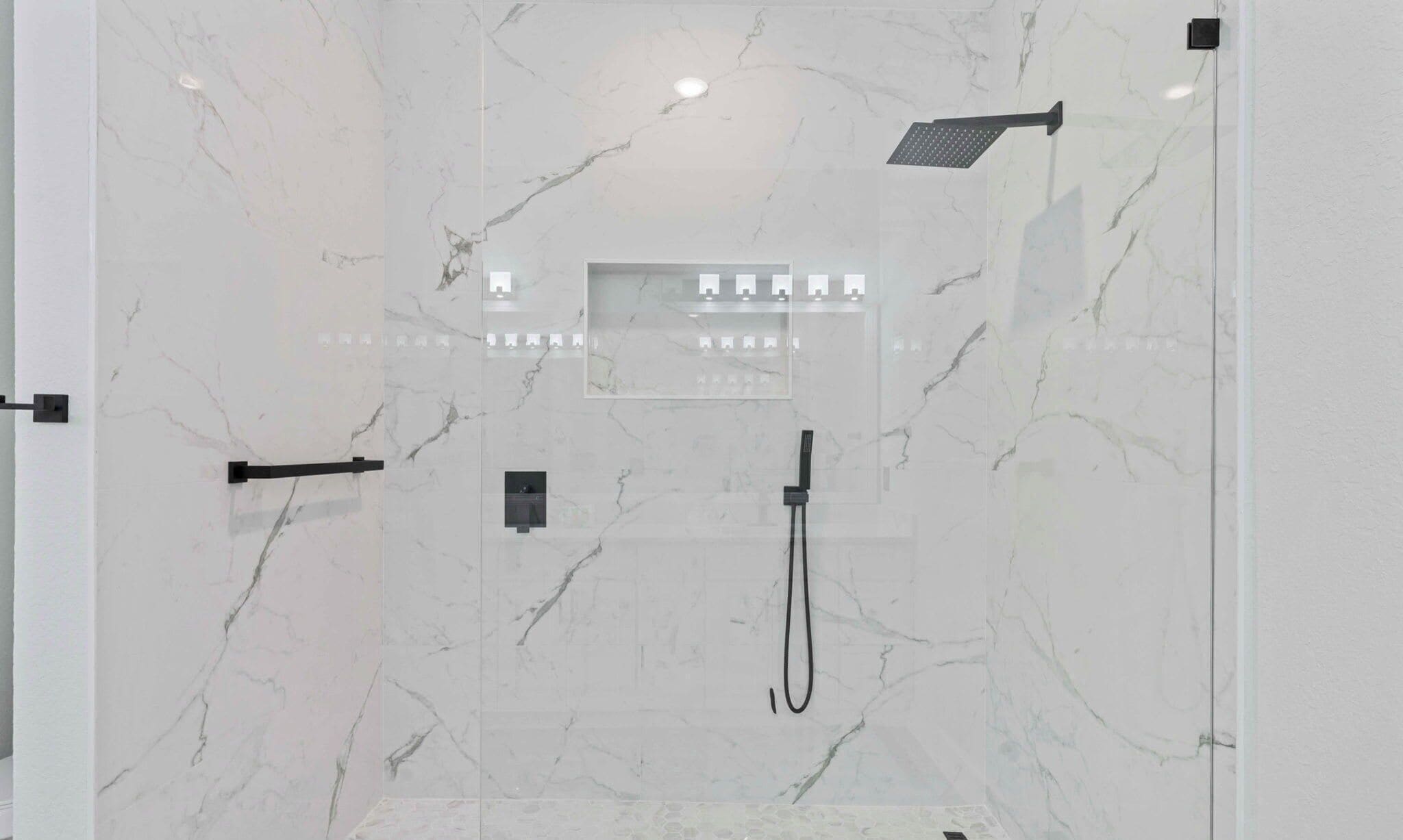 Een moderne badkamer met een douchecabine van glas, een handdouche en een bedieningspaneel op de muur.