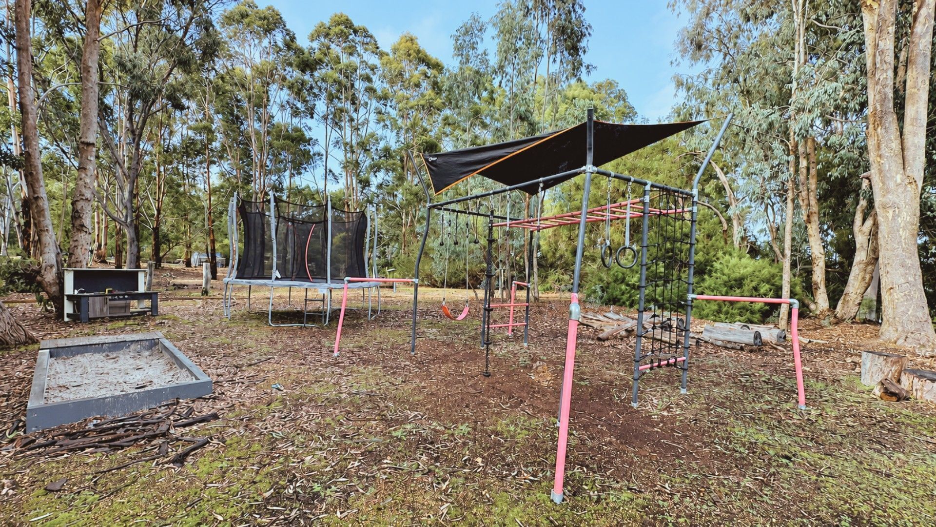 An outdoor playground with a swing set, a slide, and a climbing structure.
