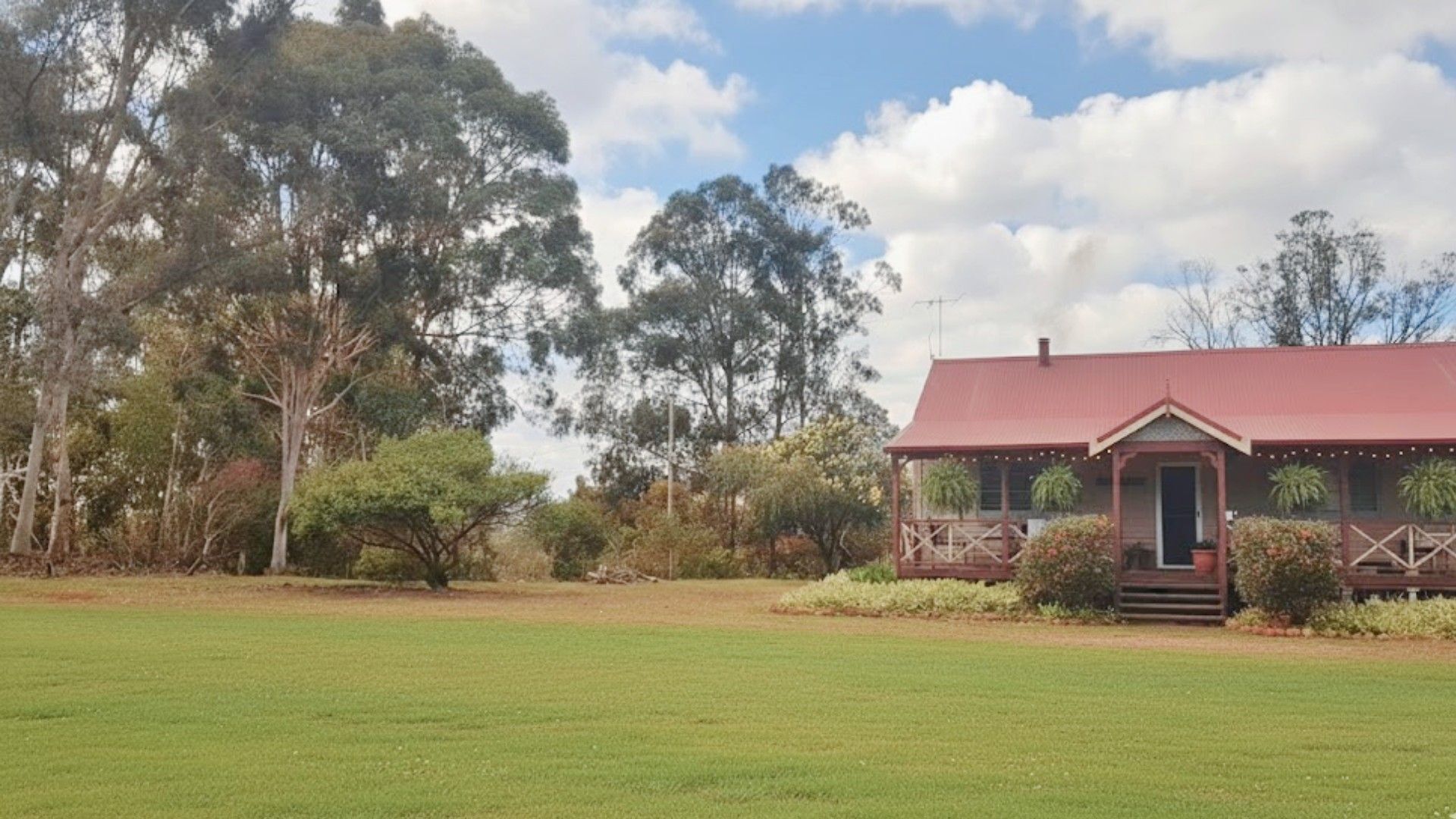 A single-story building with a red roof, surrounded by a grassy field and trees.
