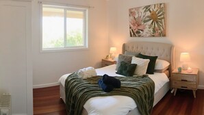 Una camera da letto con un letto, due comodini, una finestra e un'opera d'arte floreale appesa al muro.